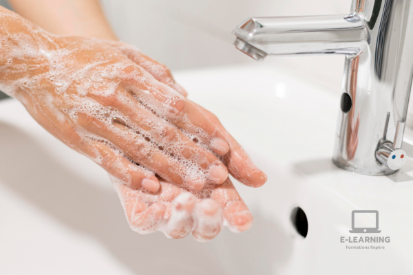 Focus sur les mains d'une personne pratiquant un lavage des mains à l'eau et au savon.