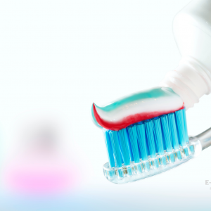 Une brosse à dent bleue recouverte de dentifrice tricolore.